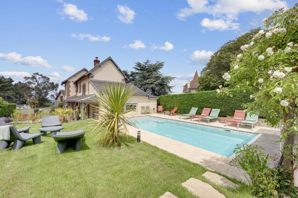 a backyard with a swimming pool and a house at Villa l'Hermitage Piscine Sauna Fitness Deauville in Bénerville-sur-Mer