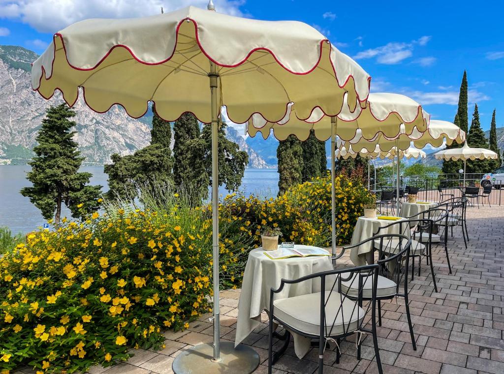 um restaurante com mesas e cadeiras debaixo de um guarda-sol em Hotel Oasi Beach em Malcesine