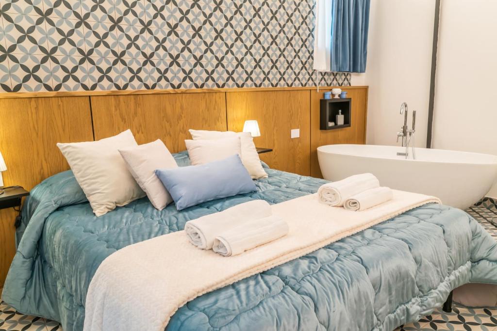 a bedroom with a large bed and a bath tub at Community Rooms & Wine in Favara