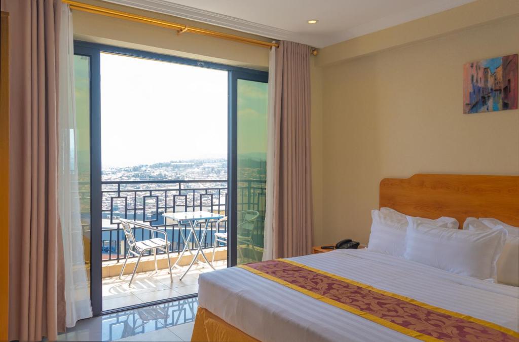 a bedroom with a bed and a large window with a balcony at Tropical Plaza Apartments in Kigali