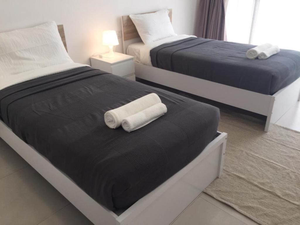 two beds in a hotel room with towels on them at Modish Classy Apartment In Jumeirah in Dubai