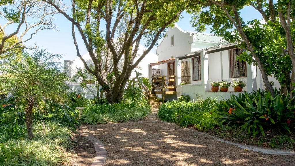een wit huis met bomen en planten bij Eastcliff Cottage in Hermanus