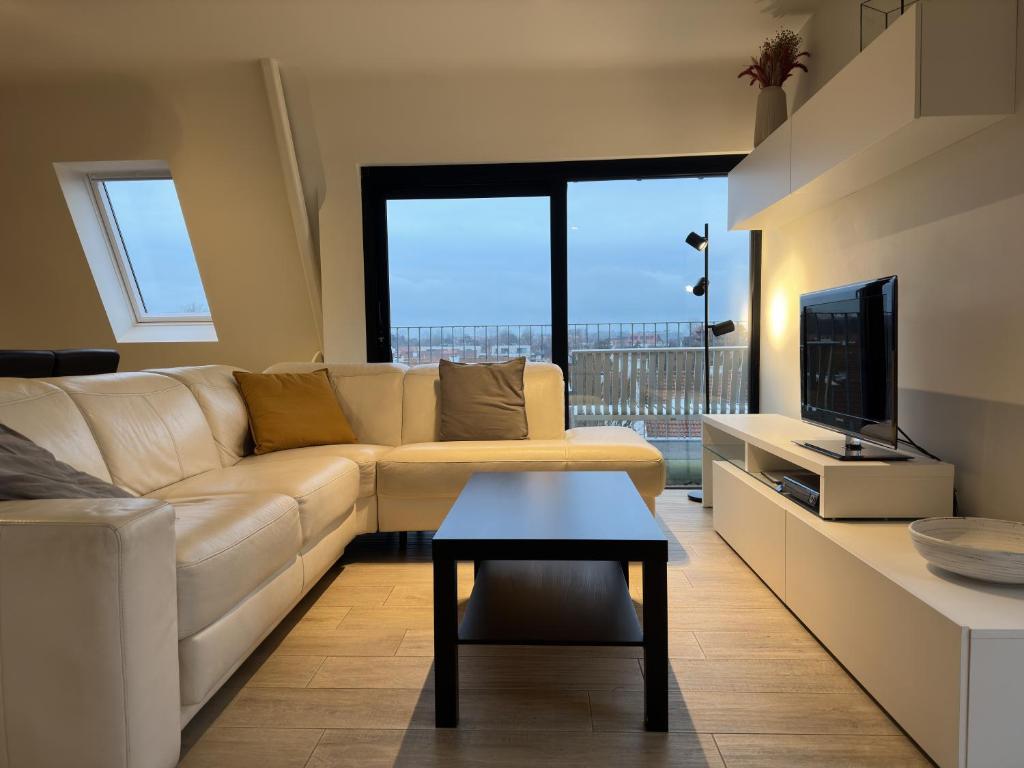 salon z białą kanapą i telewizorem w obiekcie Sea Breeze 303 w mieście Nieuwpoort