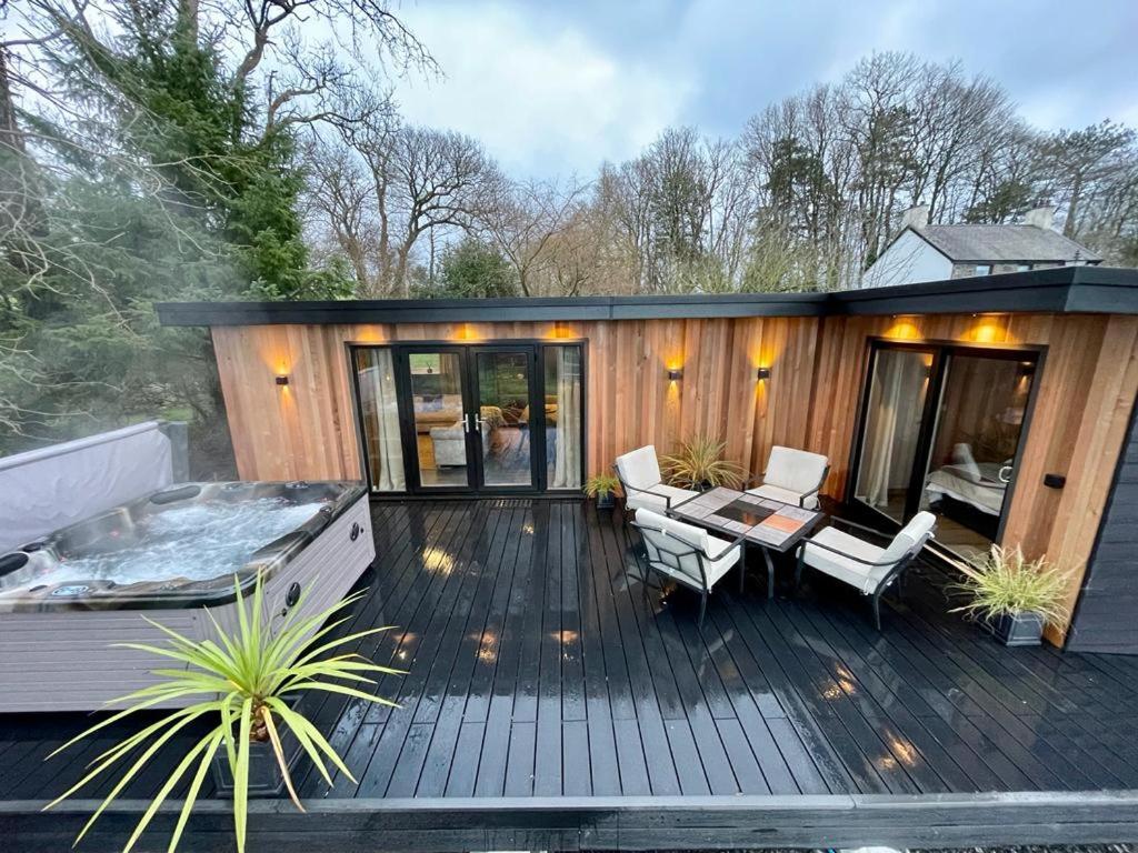 Casa con terraza de madera y bañera de hidromasaje. en The Cabin@TyddynUcha, en Caernarfon