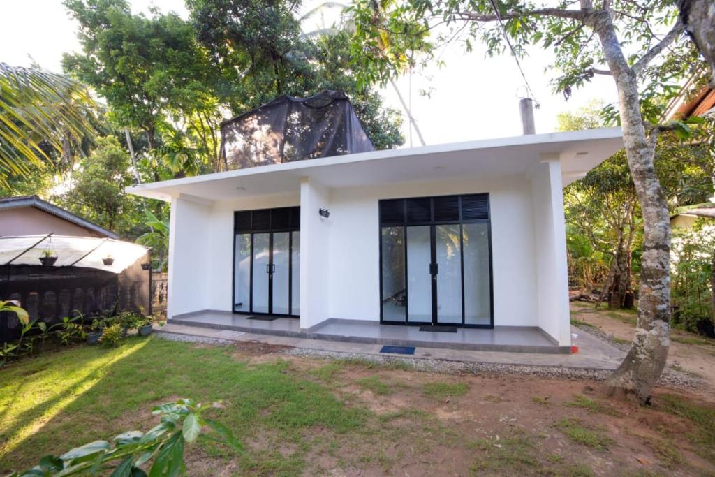 una piccola casa bianca con finestre nere di Chef Naturelle's Guest House a Kandy