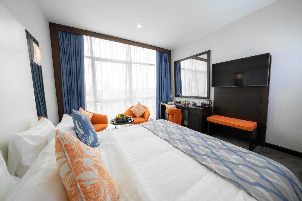 a hotel room with a large bed and a desk at Ramada Encore Doha by Wyndham in Doha