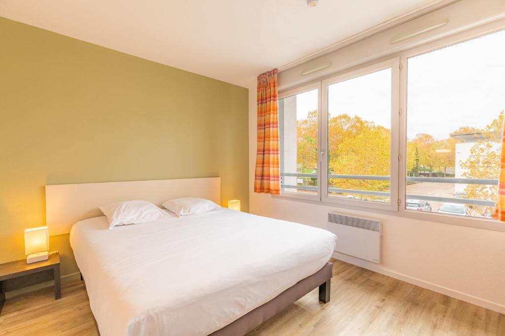 a bedroom with a bed and a large window at Appart'City Classic Bourg-en-Bresse in Bourg-en-Bresse