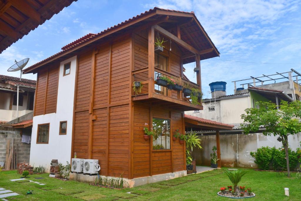 drewniany dom z balkonem na dziedzińcu w obiekcie Millicent Residence - Chalet Milly e Chalet Iris - Itaoca Praia - ES w mieście Itapemirim