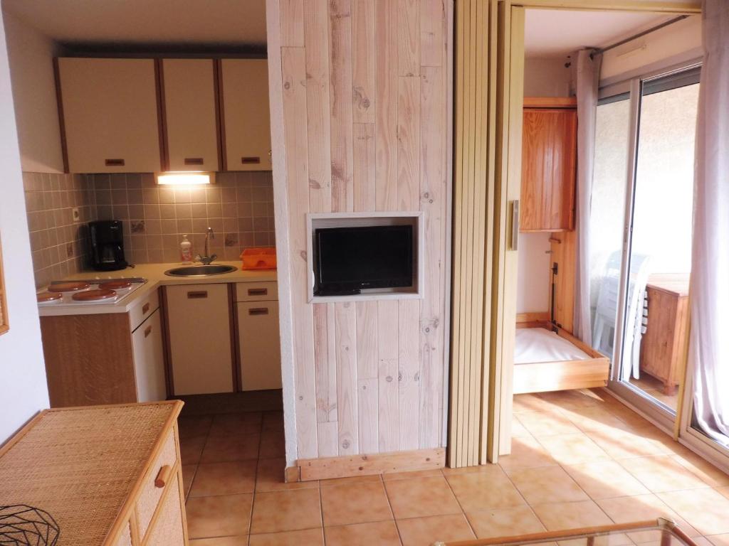 una cocina con pared y TV. en NAUTICAP Joli T2 alcôve piscine tennis NAUTICAP Plage Richelieu cap d'Agde, en Cap d'Agde