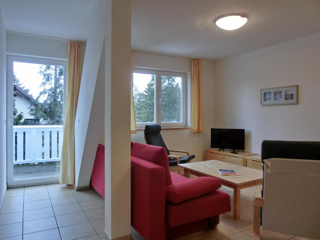 a living room with a red chair and a tv at Ferienwohnung NH14 in Hirschburg