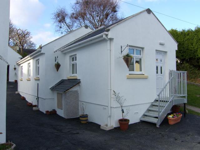 une maison blanche avec un escalier à côté de celle-ci dans l'établissement Pinfold Holiday Cottage, à Laxey