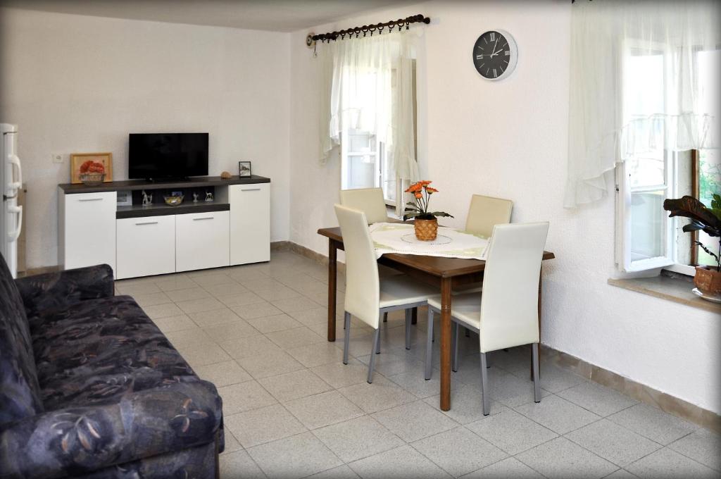 sala de estar con mesa, sillas y TV en Apartments Sunny House, en Lumbarda