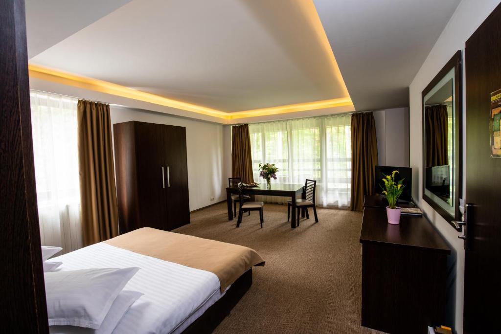 Cette chambre comprend un lit, un bureau et une table. dans l'établissement Hotel Smart, à Sinaia