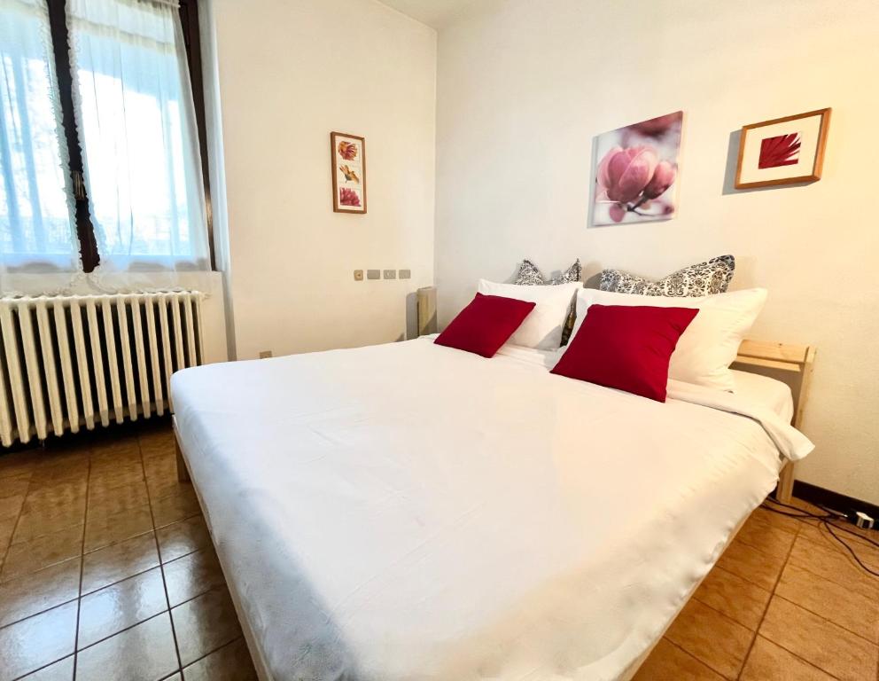 - une chambre avec un grand lit blanc et des oreillers rouges dans l'établissement GreenResidence Apartment, à Albavilla