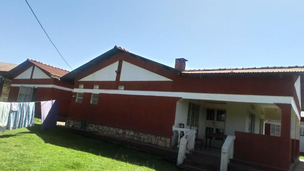 een rood-wit huis met een groene tuin bij Knowledge For Change House in Fort Portal