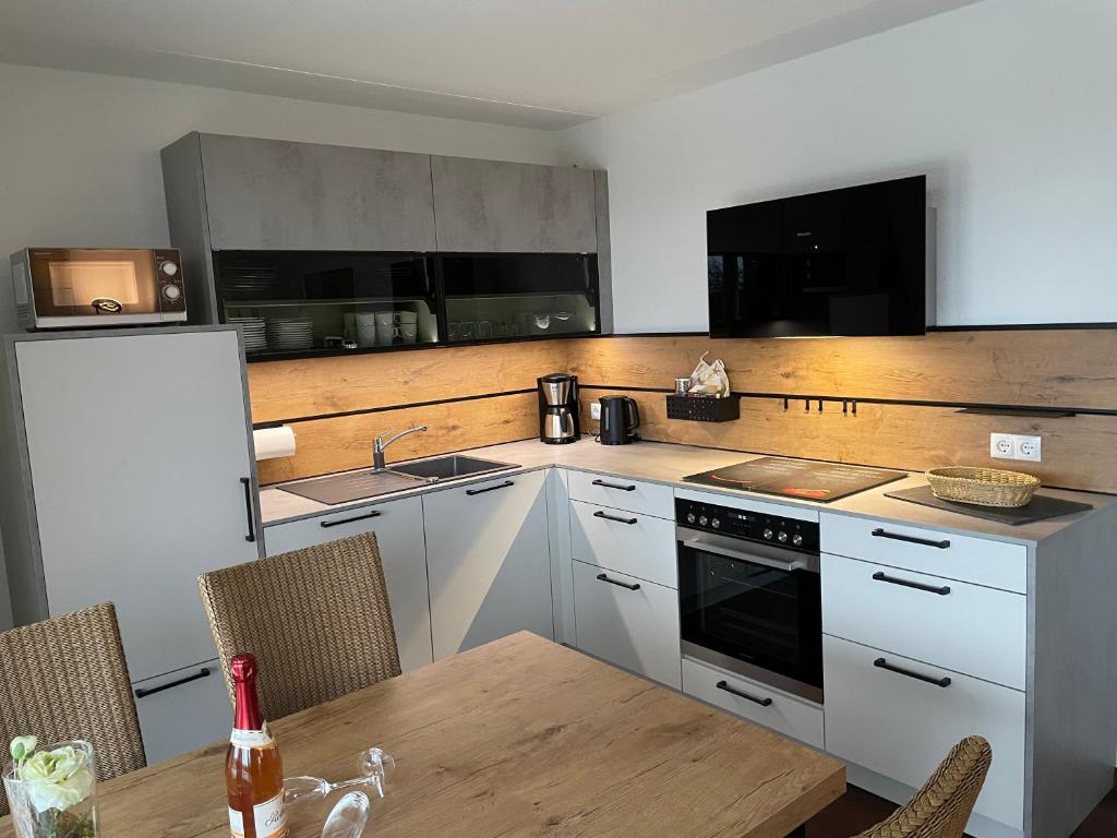 eine Küche mit weißen Schränken und einem Holztisch in der Unterkunft Ferienwohnungen Residenz Hohe Lith - Duhnen in Cuxhaven
