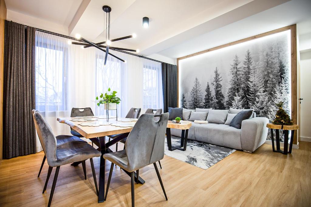 a living room with a table and a couch at VisitZakopane - Radowid Loft Spa Apartment in Zakopane