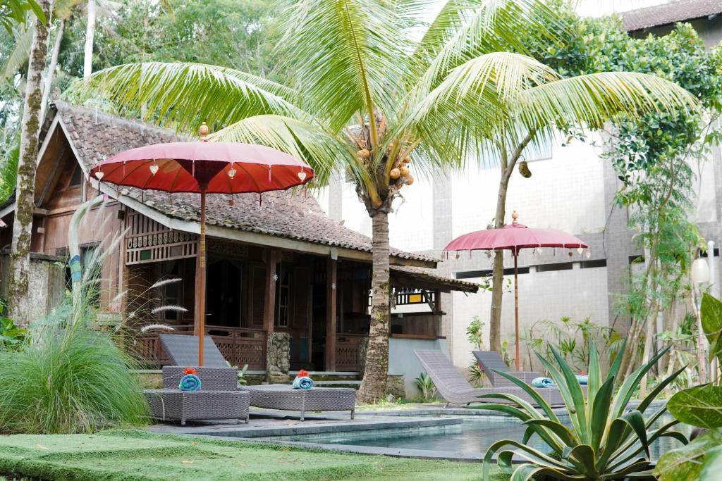 a resort with two red umbrellas and a pool at Sentana Villa Ubud in Ubud