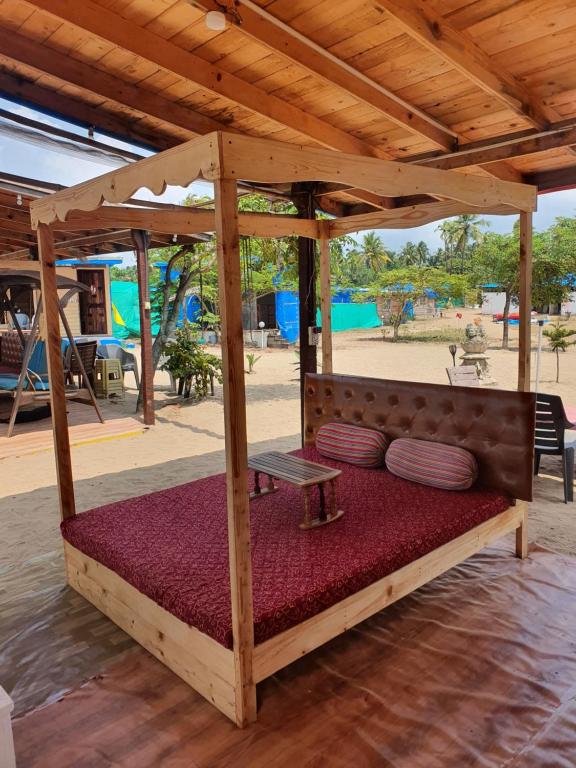 a bed under a wooden canopy with pillows on it at Love Temple Beach Resort in Arambol