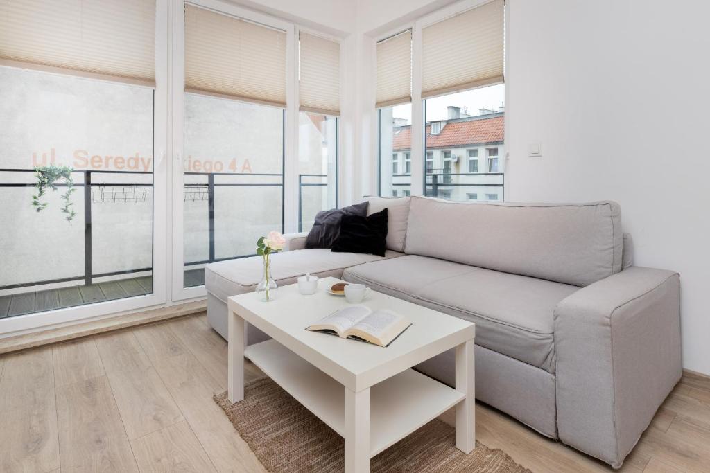 een woonkamer met een bank en een tafel bij Nowa Grobla Estate Apartment near Starówka by Renters in Gdańsk