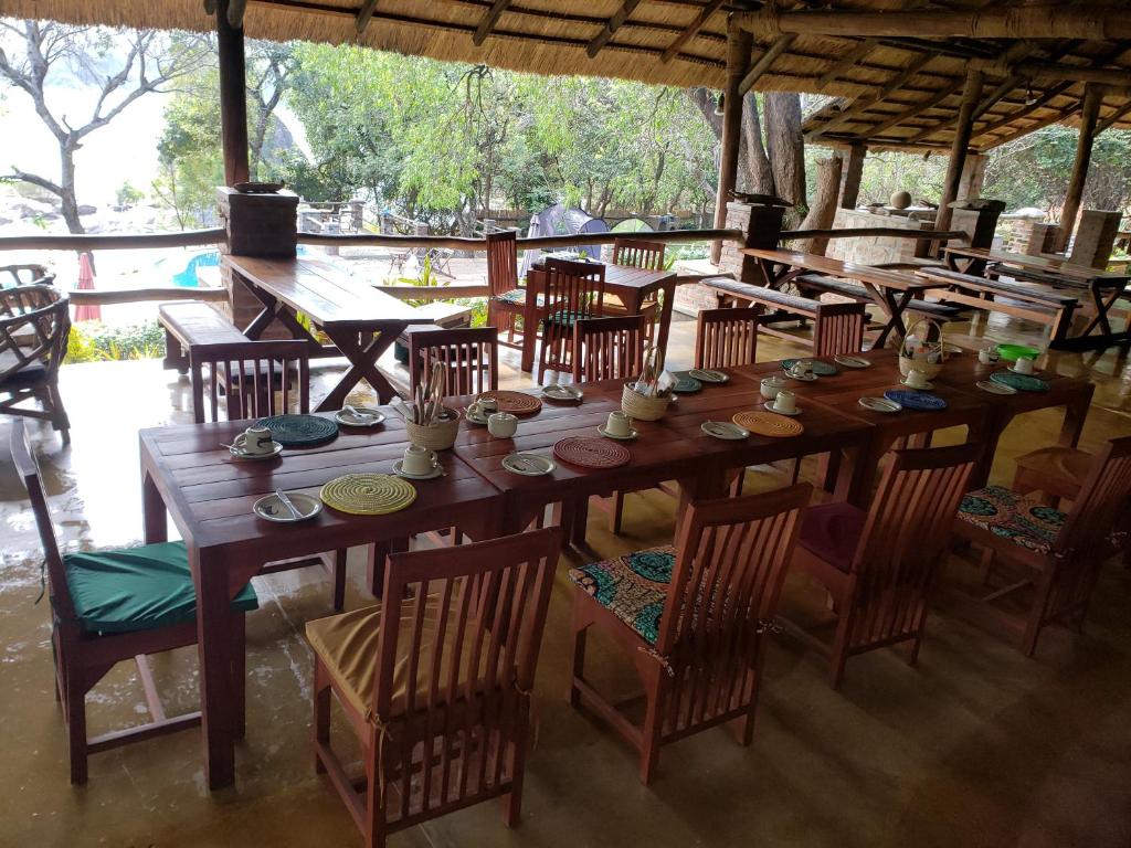 una gran mesa de madera y sillas en un restaurante en Ng'ona Lodge en Maganga