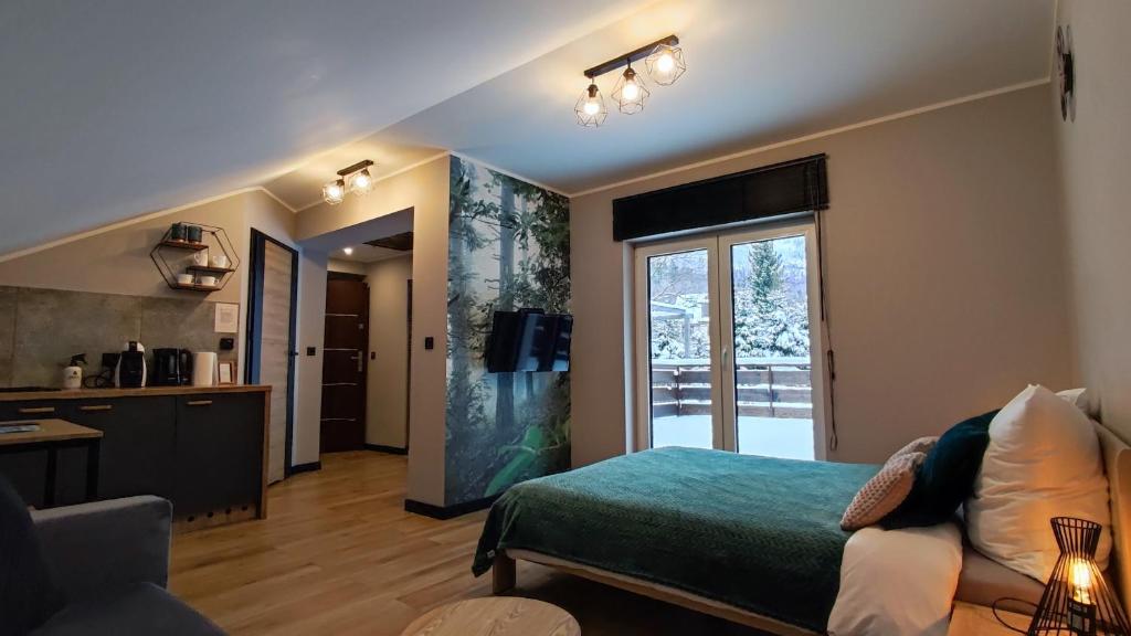 ein Wohnzimmer mit einem Bett und einer Küche in der Unterkunft Apartament Olimpijska 54 z prywatnym jacuzzi na tarasie in Szczyrk