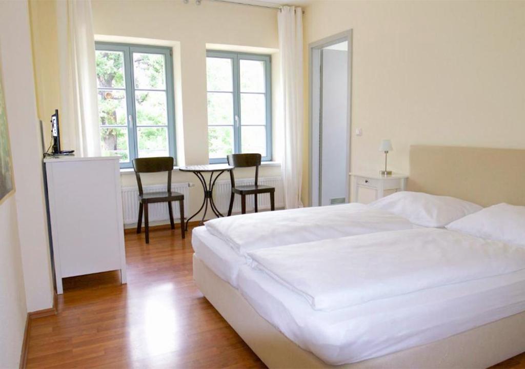 1 dormitorio con cama blanca y mesa con sillas en Hofgarten 1824 Hotel garni, en Dresden