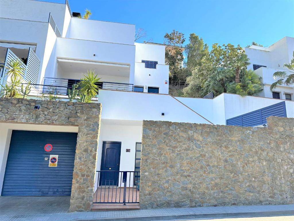 une maison blanche avec une porte bleue et un mur en pierre dans l'établissement Magnifica casa con jacuzzi y cerca playa ref 160, à Montjoys