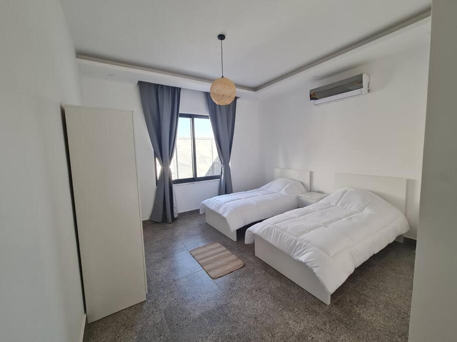 a bedroom with two beds and a window at VIBES Chalet in Dead sea in Al Rama