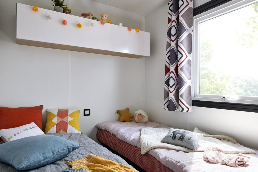 a bedroom with two beds and a window at Camping Mussonville in Soulac-sur-Mer