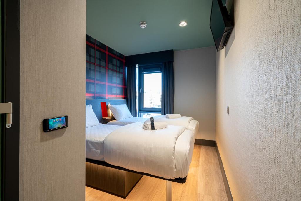 um quarto com uma cama branca e uma janela em easyHotel Dublin em Dublin