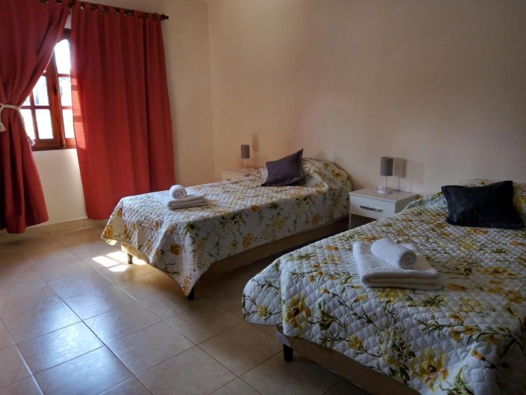 a bedroom with two beds and a window with red curtains at Lo de Chavela in Salta