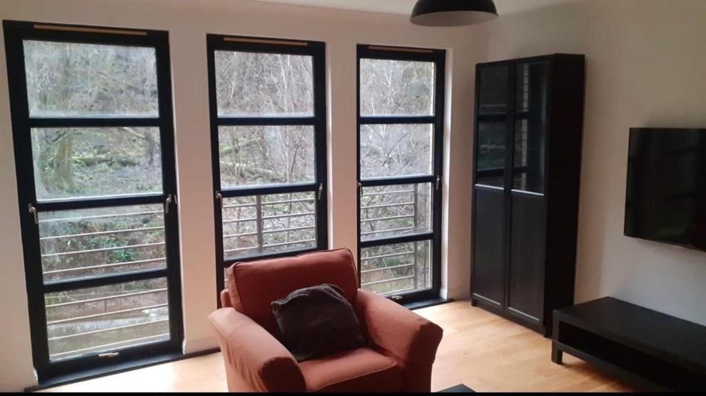 sala de estar con silla y 4 ventanas en Duntocher village flat, en Clydebank