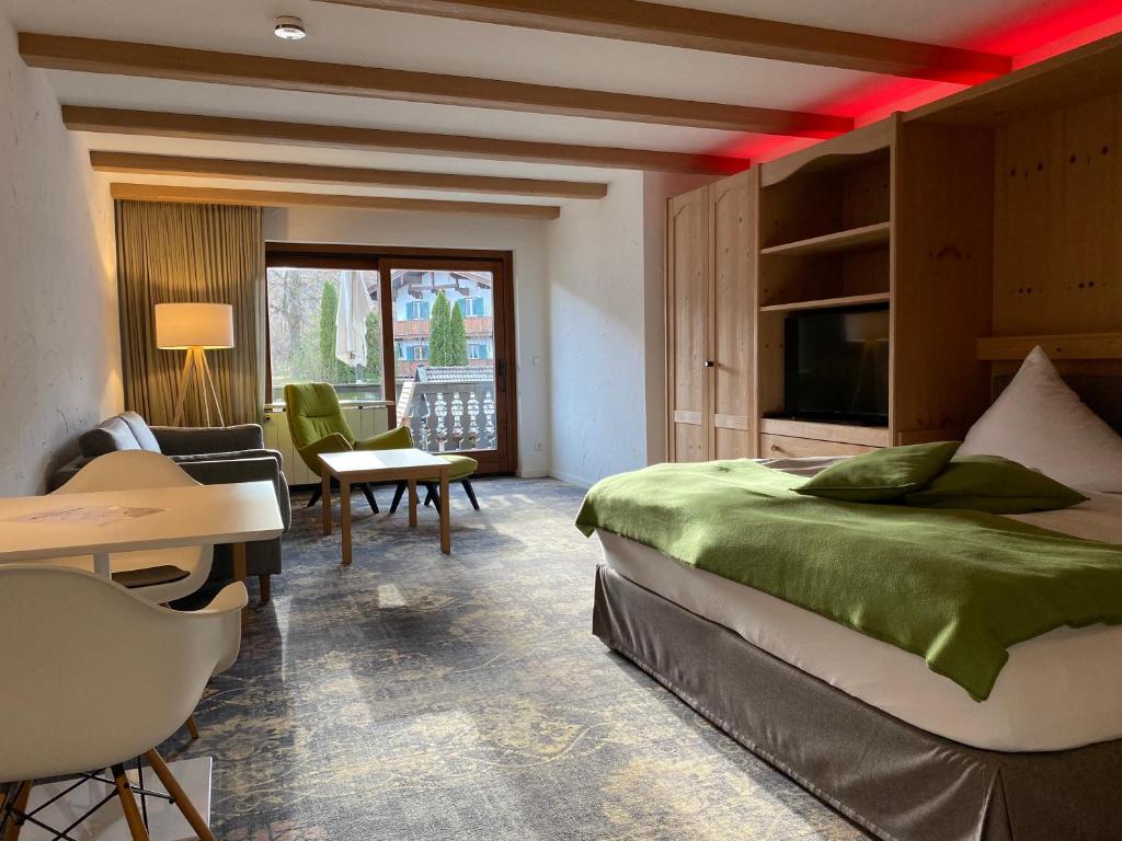 ein Hotelzimmer mit einem Bett, einem Schreibtisch und einem TV in der Unterkunft Sonnhof Apartments Tegernsee - zentral und perfekt für Urlaub & Arbeit in Bad Wiessee