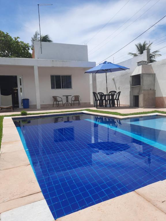- une piscine avec un parasol en face d'une maison dans l'établissement Casa Vitória em barra de jacuipe, à Campos