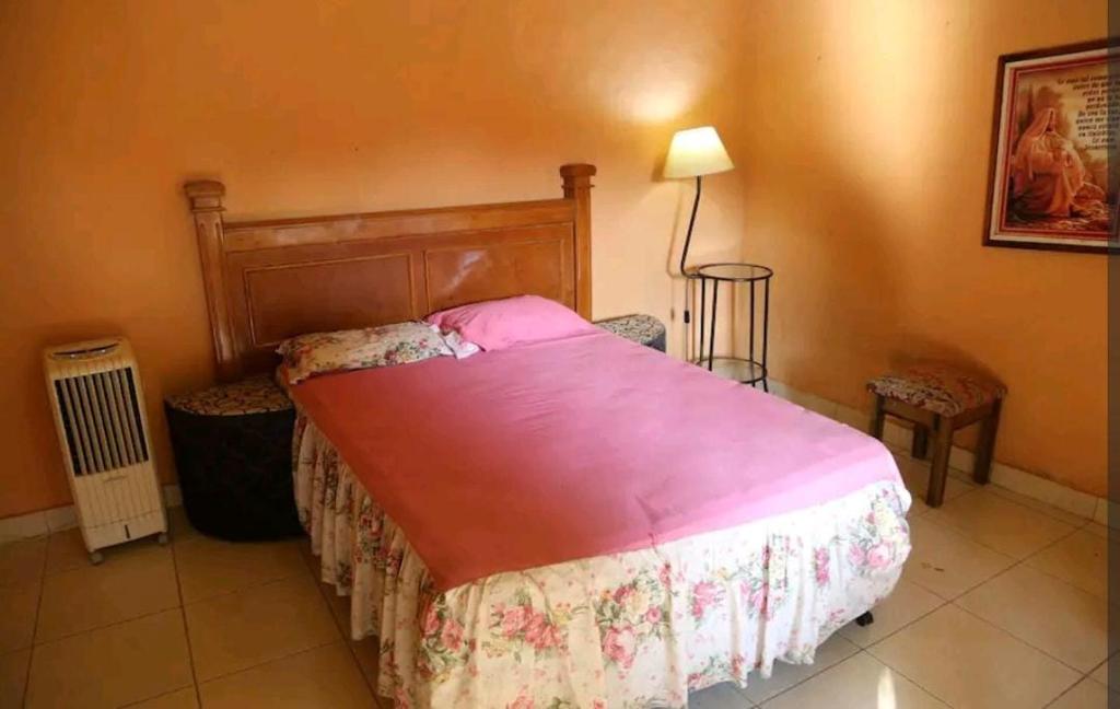 a bedroom with a bed with a pink blanket at La Ponderosa in Asuncion
