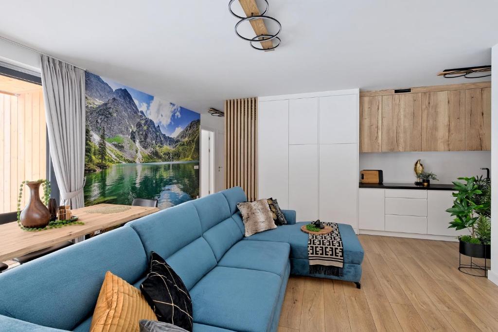 un sofá azul en la sala de estar con un mural de montaña en Apartament Morskie Oko Odkryj Zakopane, en Zakopane