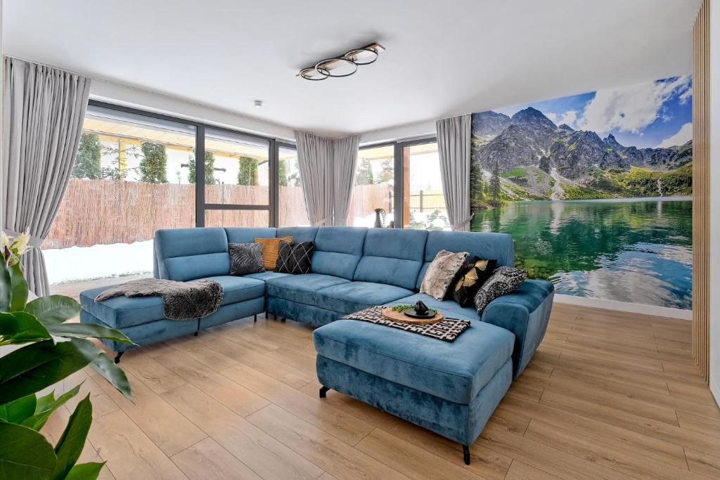 a living room with a blue couch and a large window at Apartament Morskie Oko Odkryj Zakopane in Zakopane