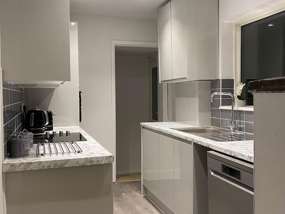 a kitchen with white cabinets and a counter top at Splendid Stays by Citybricks in Kent