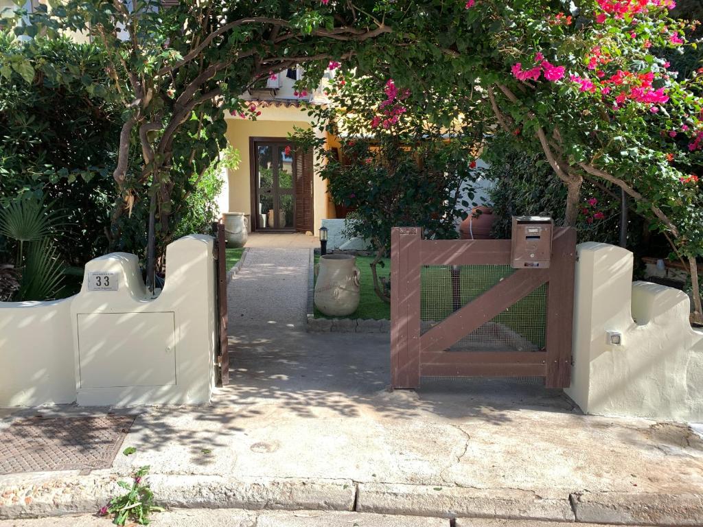 una puerta de madera frente a una casa con flores rosas en Villa del Brigante, 200m from the beach, 80m², 2 bedrooms, 4-5 persons, en Capitana