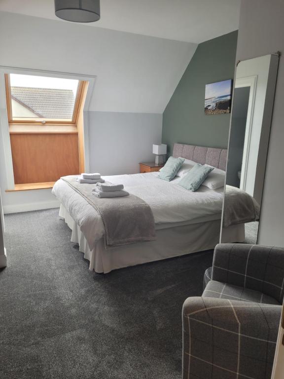 a bedroom with a bed and a window and a chair at Lindisfarne Bed & Breakfast in Stromness