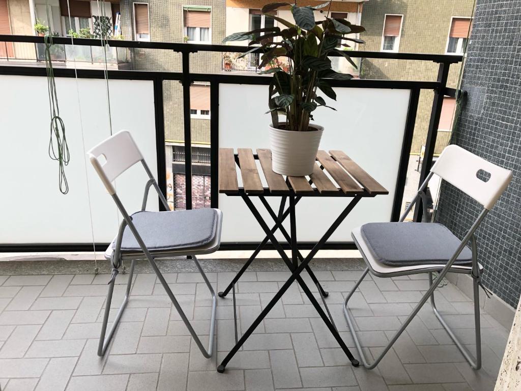 d'une table, de deux chaises et d'une plante en pot sur un balcon. dans l'établissement Casa Cavaleri Sweet apartment MM Bande Nere, à Milan