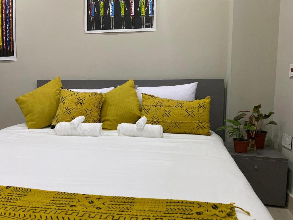 uma cama com almofadas amarelas e toalhas brancas em Newly Renovated 1Bd Apt in Heart of Osu em Acra