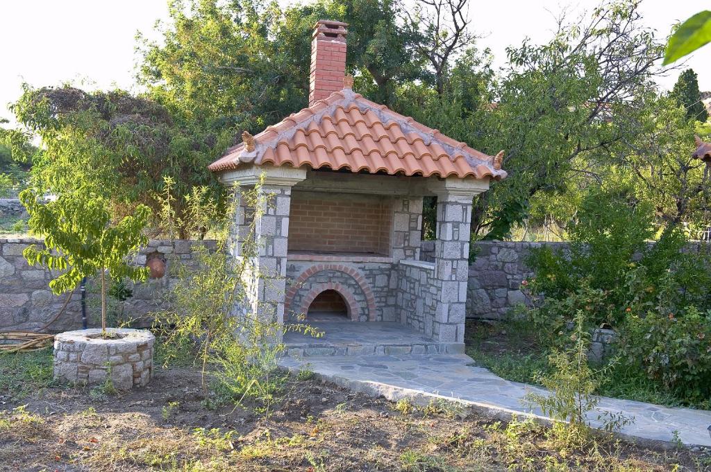 a small house with a brick fireplace in a yard at Artemis Traditional Hotel in Myrina