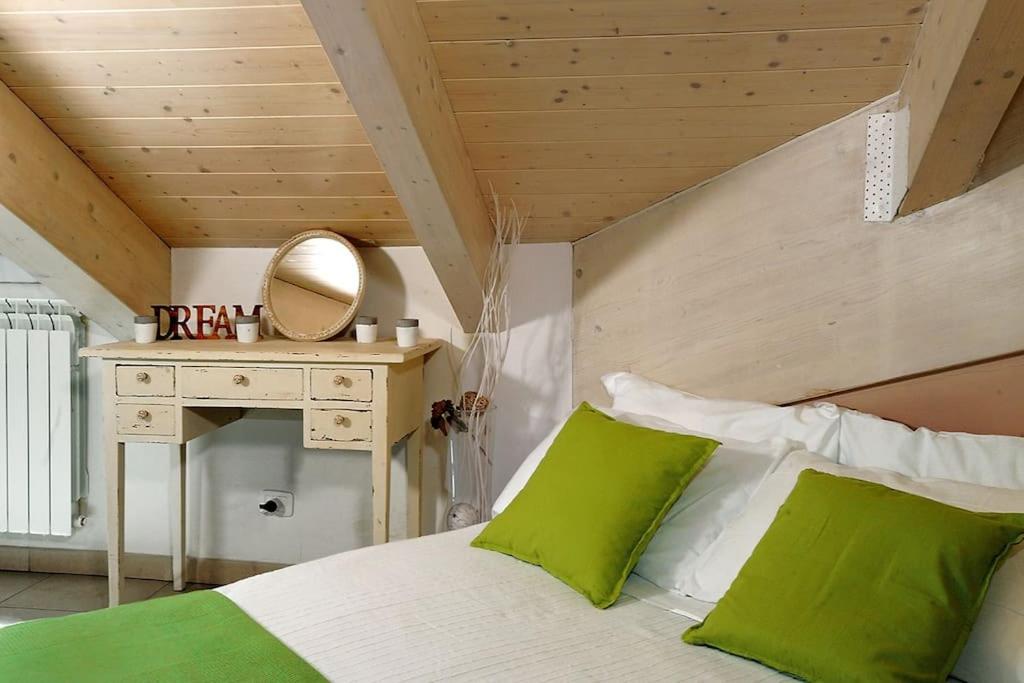 um quarto com uma cama com almofadas verdes e um espelho em A un passo da Porta Nuova e dal centro: Io&Te em Turim
