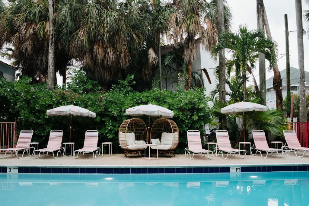 een groep stoelen en parasols naast een zwembad bij Selina Miami River in Miami