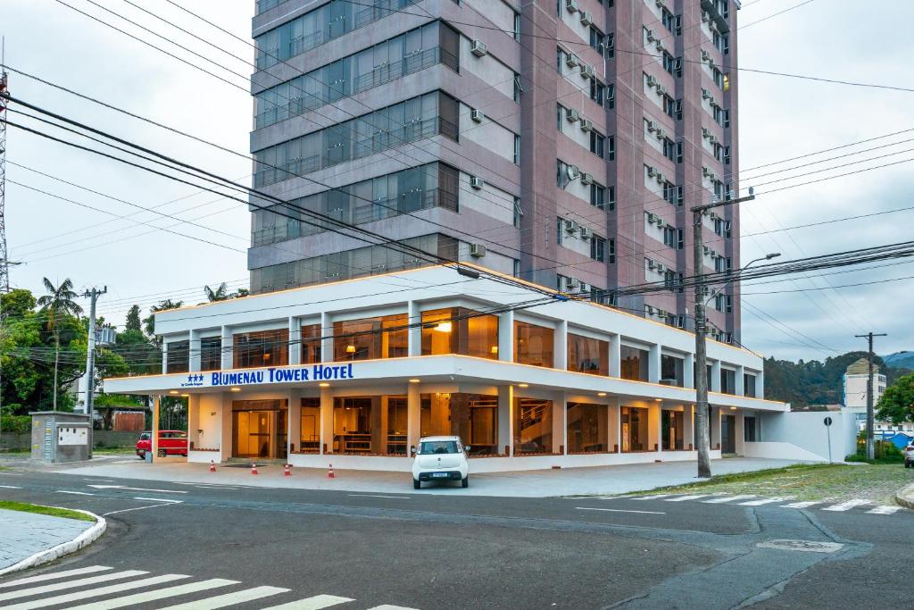 um edifício com um carro estacionado em frente em Blumenau Tower by Castelo Itaipava em Blumenau