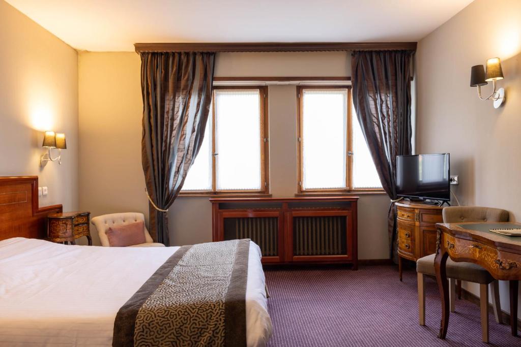 a hotel room with a bed and a television at Parc Hôtel in Wangenbourg