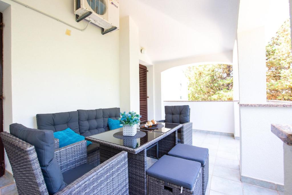 patio z wiklinowymi meblami, stołem i krzesłami w obiekcie Apartments Ela w Novalji