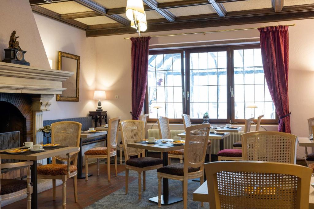 a dining room with tables and chairs and a fireplace at Parc Hôtel in Wangenbourg